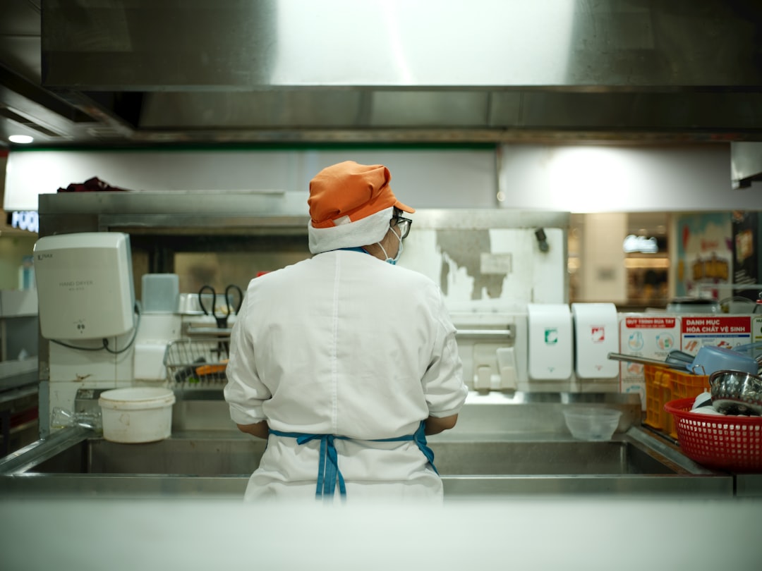 Technician servicing commercial kitchen equipment, inspecting stainless steel cooking station