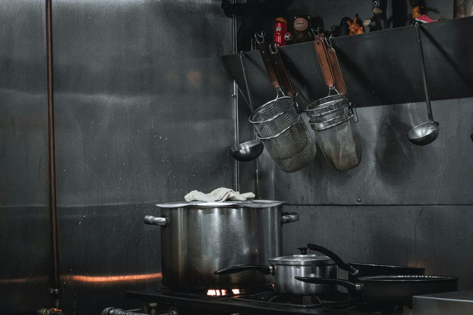 Commercial kitchen equipment station with stainless steel cookware and industrial prep surfaces